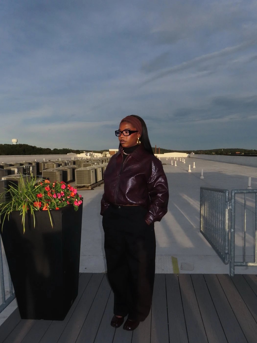 Woman in a burgundy leather jacket on a rooftop at dusk