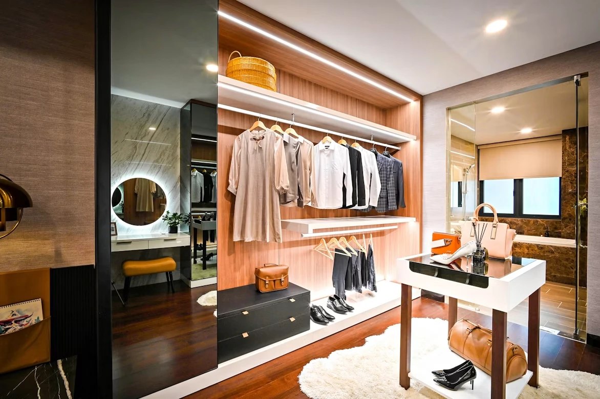 Organized walk-in closet with hanging clothes, shelving, and a styling vanity